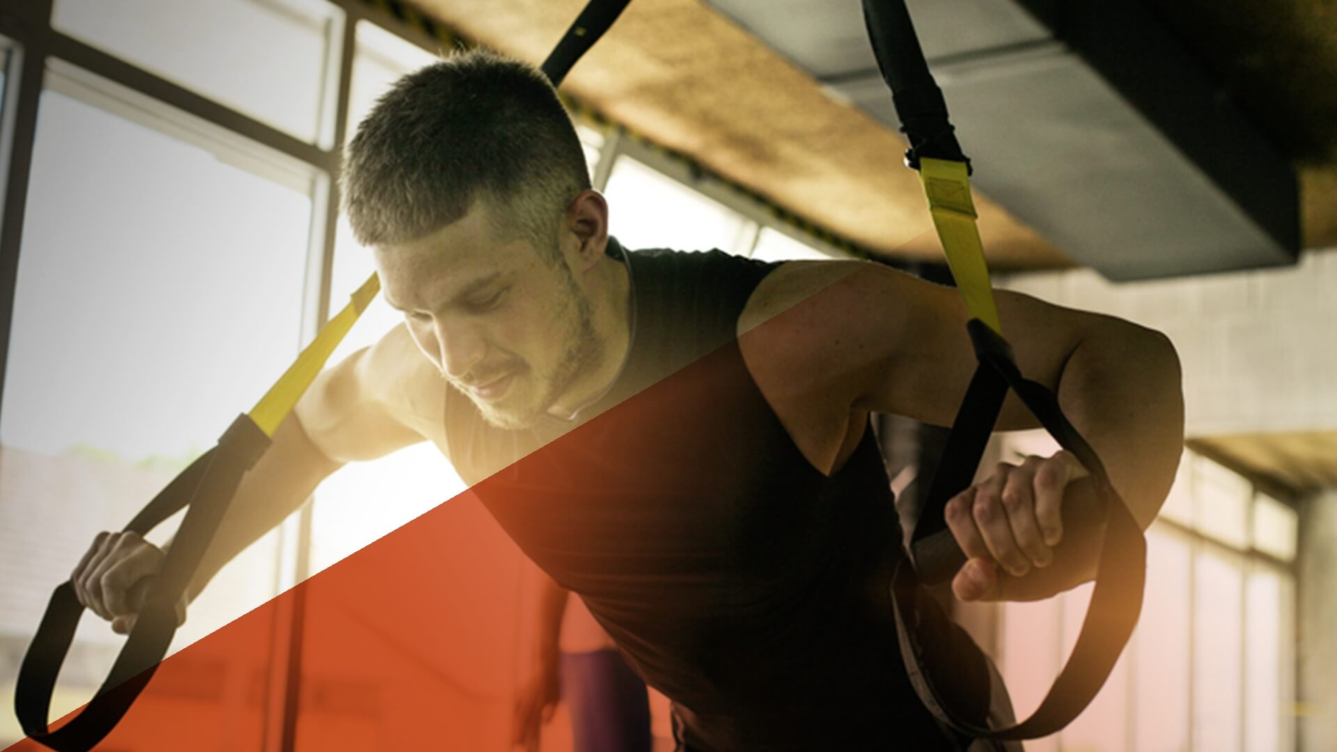 Ein junger Mann trainiert mit TRX-Schlaufen im Fitnessstudio.