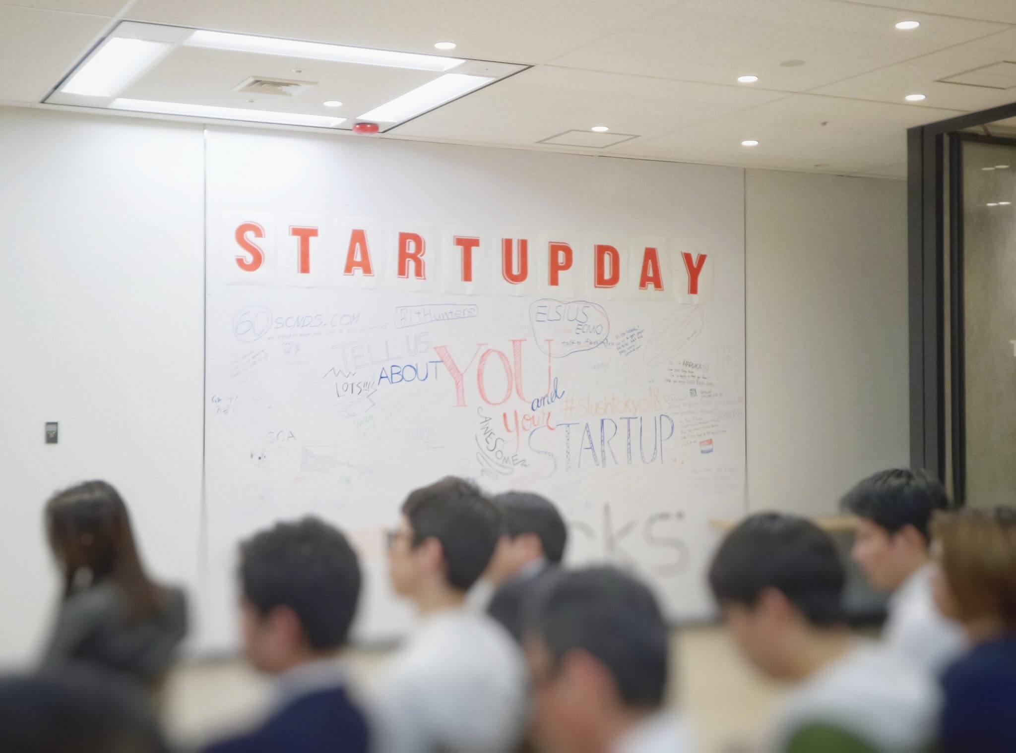 Whiteboard vor einem Publikum mit dem Slogan - Start Up Day