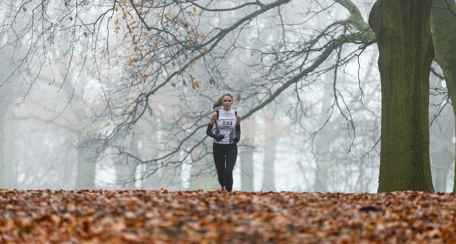 Eine Frau läuft im Wald bei winterlichem Wetter im Nebel