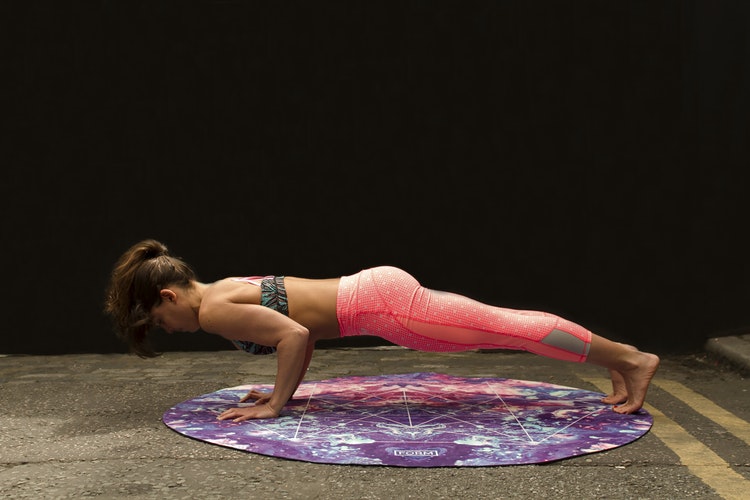 Eine Frau in einer Fitnessposition auf dem Boden mit einer pinken Leggings