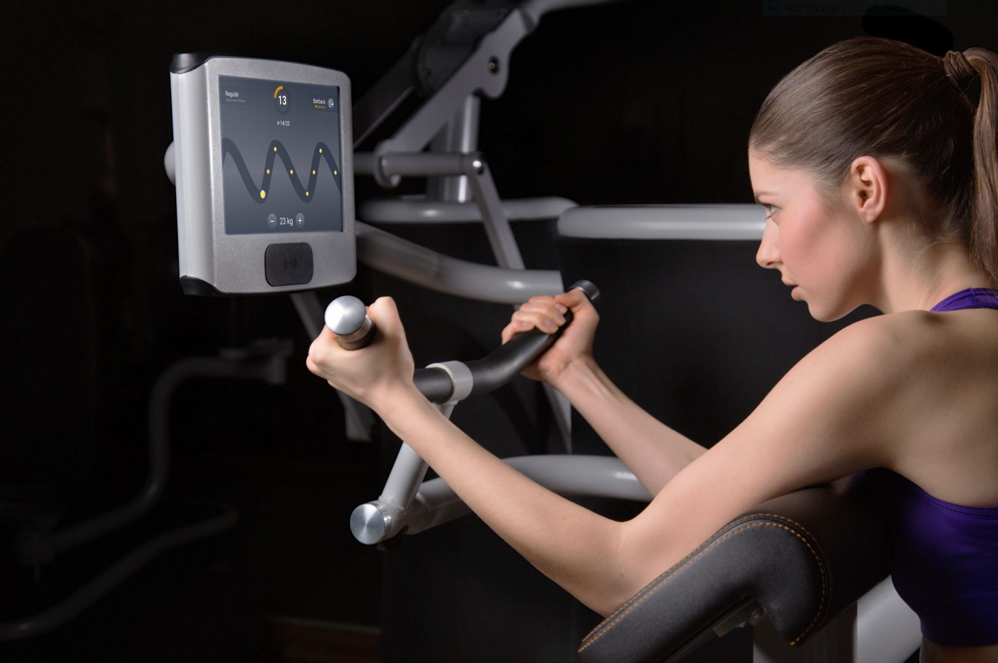 Eine Frau an einem eGym Gerät bei einem Training mit einem dunklem Hintergrund